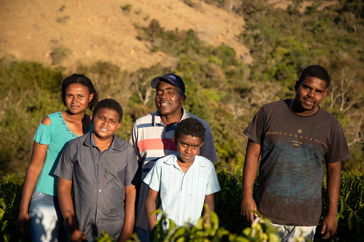 A family of five standing together in front of coffee and a dry hillside