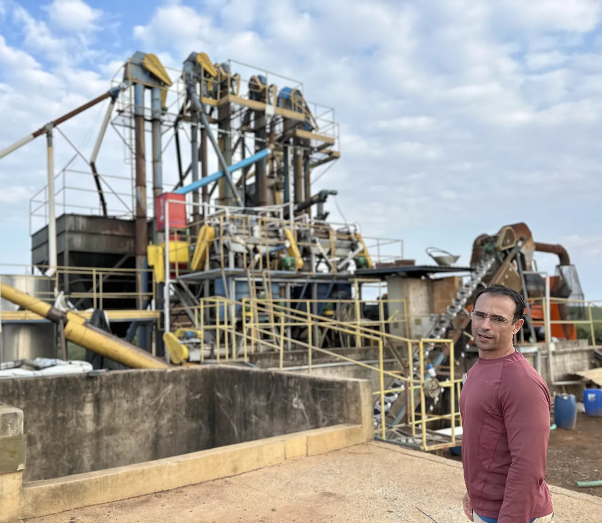 Producer standing by the coffee processing equipment at Fazenda Terra Alta